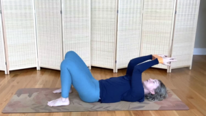 Woman lying on the floor doing Pilates exercises with a loop band.