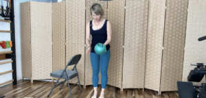 Woman standing with a ball doing Pilates exercises.