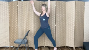 Woman standing in a lunge next to a chair doing Pilates.