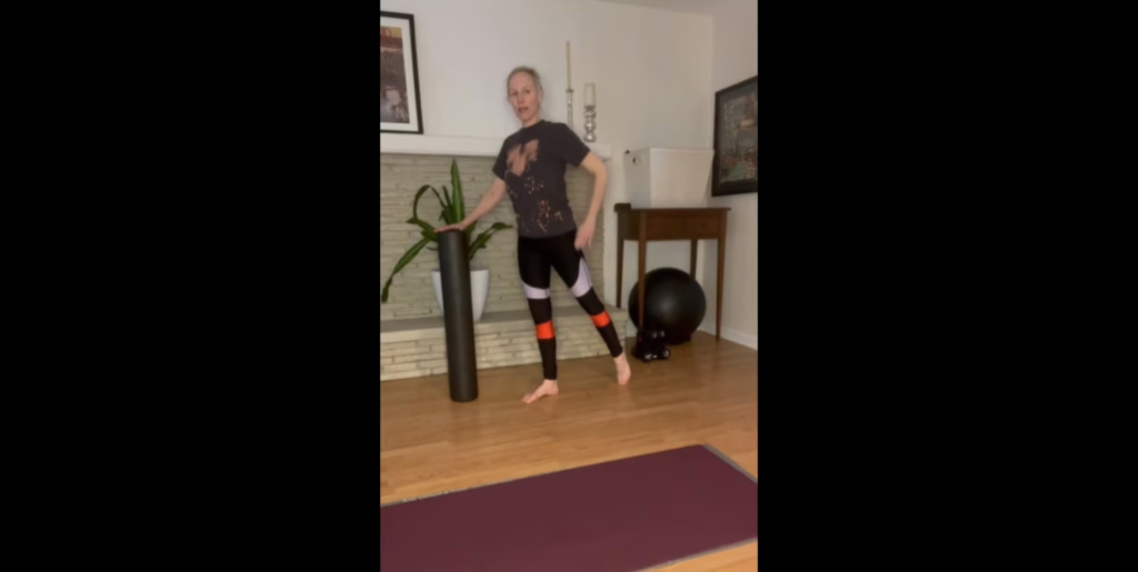 Woman doing standing Pilates exercises with a foam roller for fitness mobility and strength