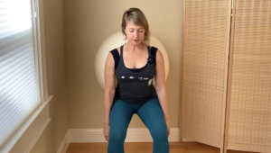 Woman doing a Pilates squat against the wall with a ball.