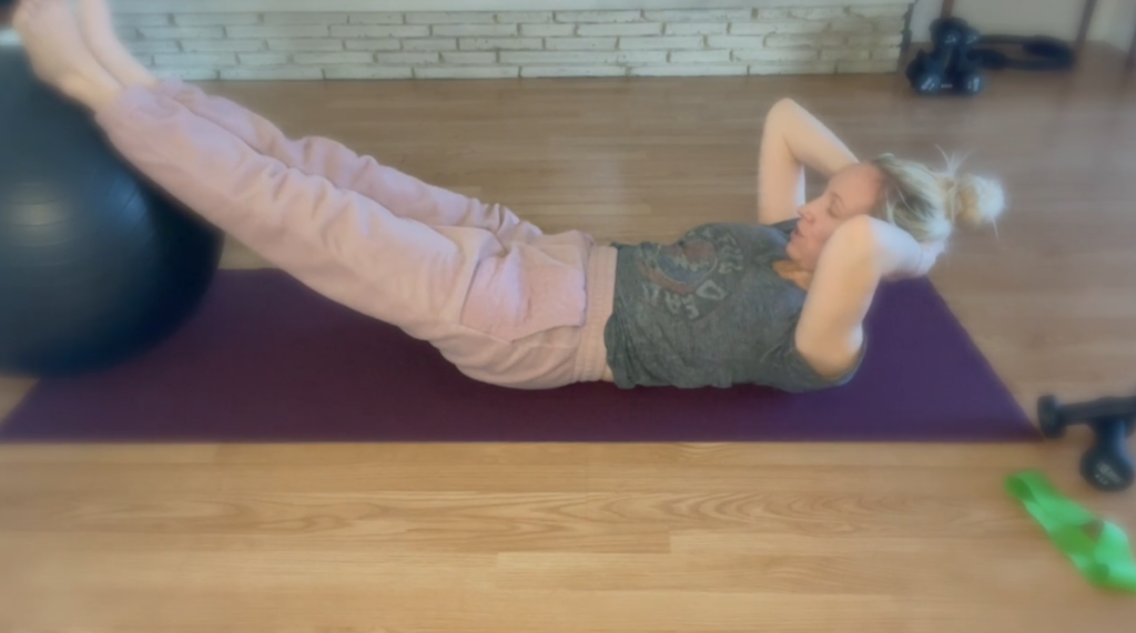 Woman on floor doing Pilates exercises with a big ball for health