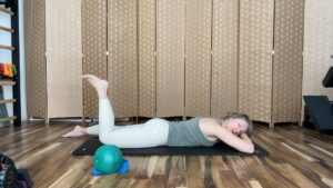 Woman doing Pilates exercises on the floor bending her leg for fitness and strength