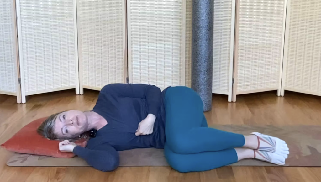 Woman lying on her side doing Pilates exercises on the floor.