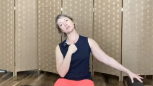 Woman sitting on a Pilates mat doing neck stretches