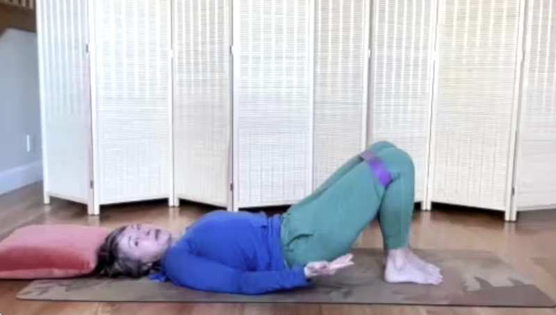 Woman lying on the mat doing Pilates exercises with a loop band for fitness and strength