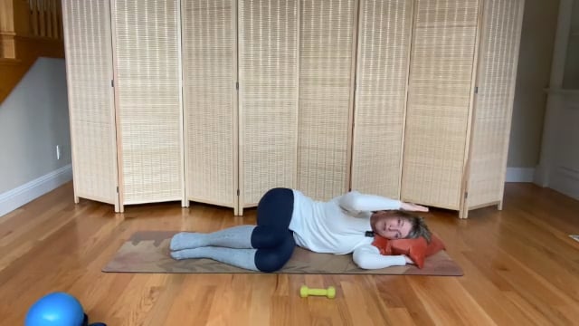 Woman doing Pilates arm exercises lying on the floor for fitness and strength