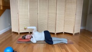 Woman doing Pilates arm exercises on the floor and holding weight in hand for fitness and strength