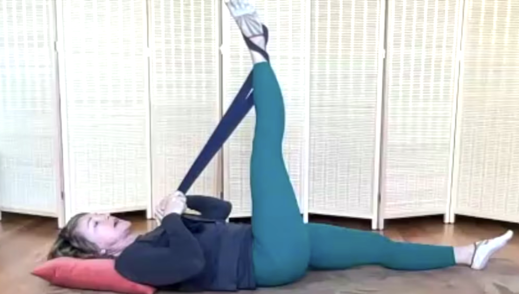 Woman doing Pilates exercises on the floor stretching one leg up