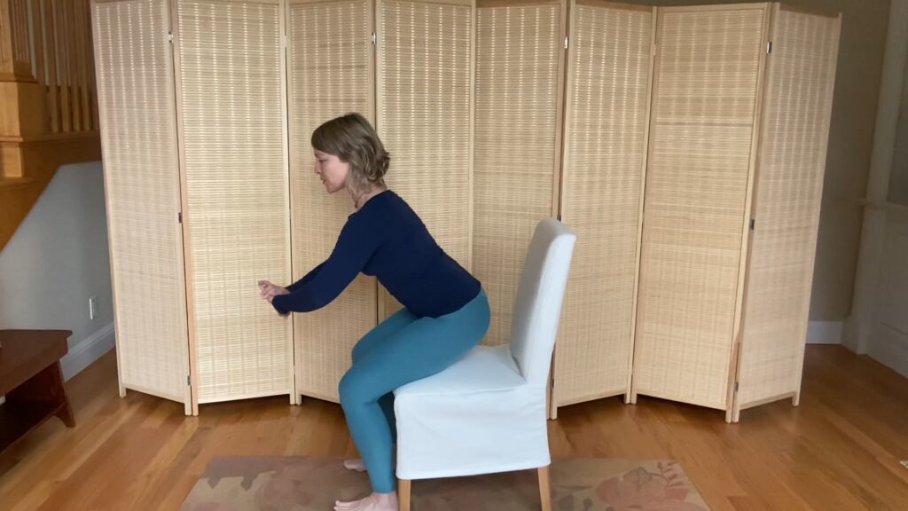 Woman doing Pilates squat exercises on a chair for fitness and strength to prevent falls