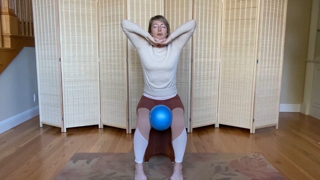 Woman doing Pilates exercises on a chair with a small ball