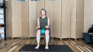 Woman doing Pilates exercises on a chair with a small ball for fitness and strength