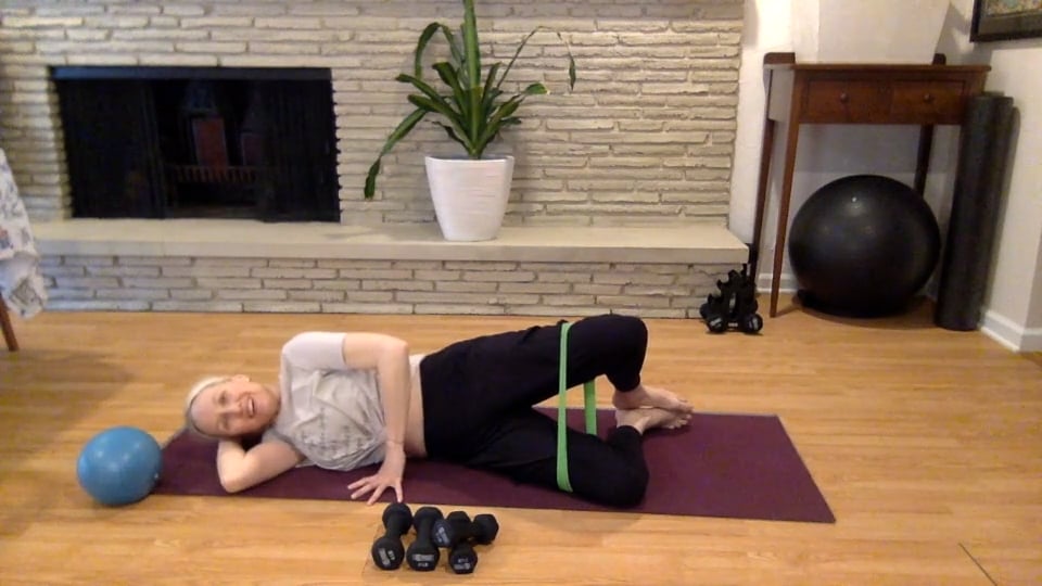 Woman doing Pilates with various PIlates props like weights bands and balls.