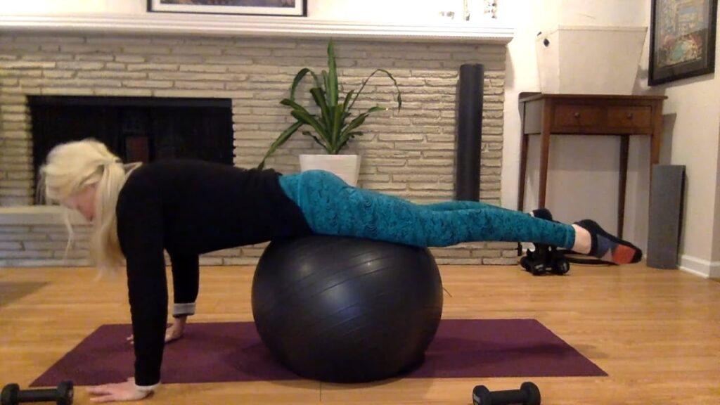 Woman doing Pilates plank with stability ball.