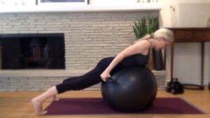 Woman doing Pilates on stability ball with weights.