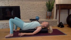 Woman doing Pilates on a foam roller on the mat.