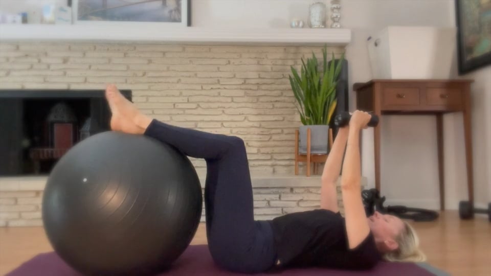 Woman doing Pilates with weights and a ball.