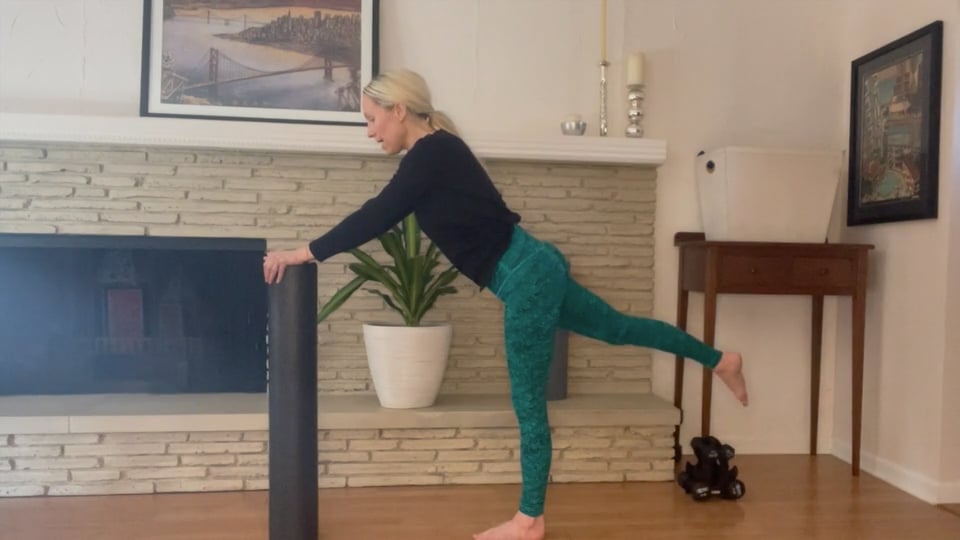 woman doing standing leg exercises with foam roller