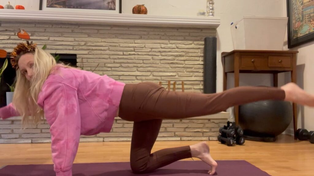 woman doing bird dog pilates exercise on mat